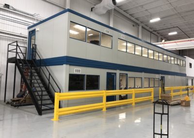 Side profile of two-tier modular office upon completion with staircase, yellow guardrail